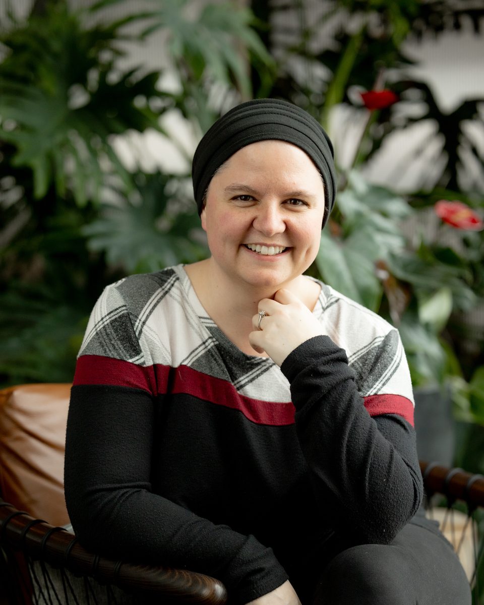 Alli Kaeppel, founder of Pallas Cloud, smiling and seated in a leather chair in front of green plants